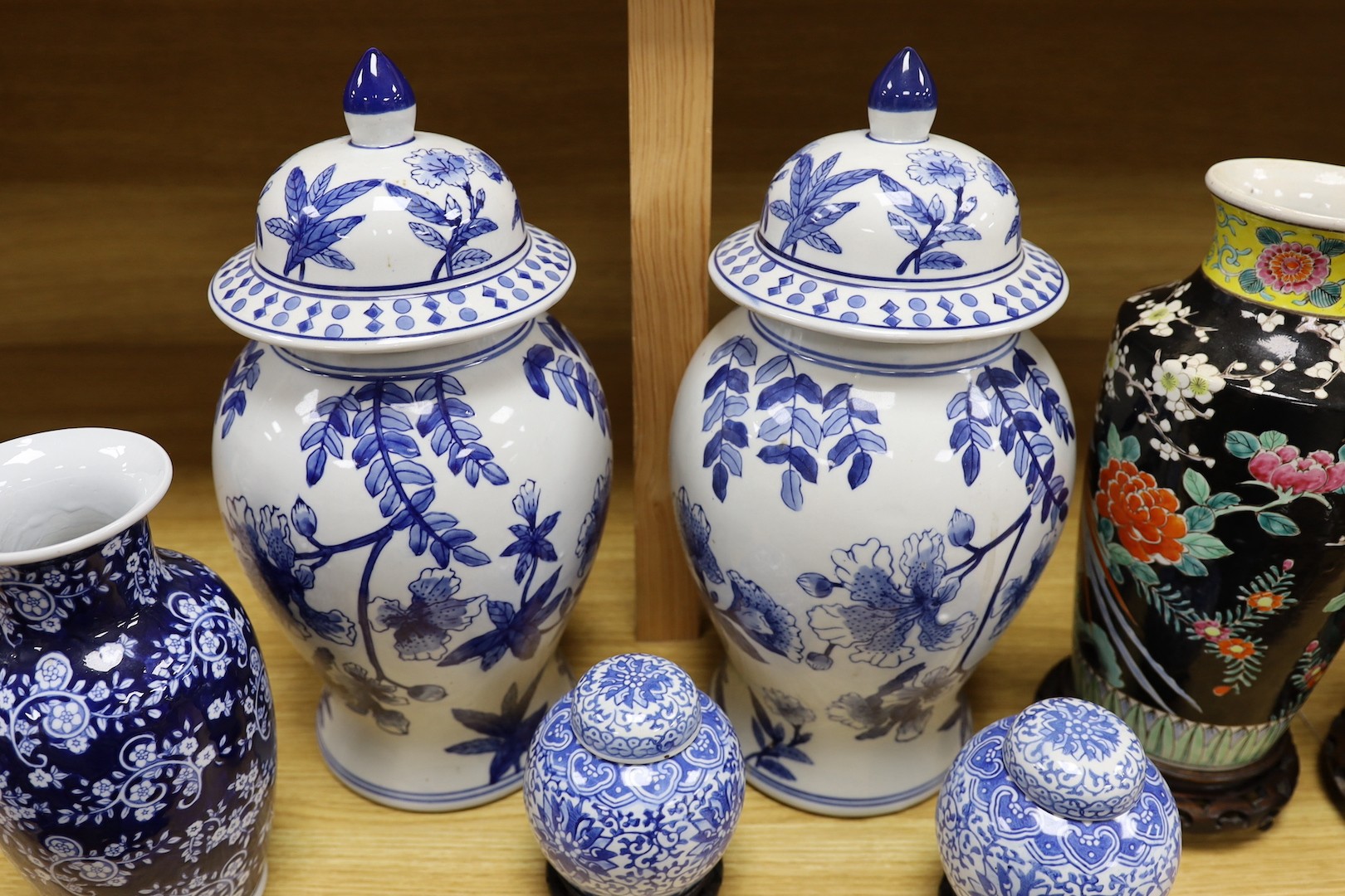 A pair of Japanese black ground vases, a pair of Chinese blue and white vases and covers, a similar pair of jars and a vase, four wood stands. Largest 41cm